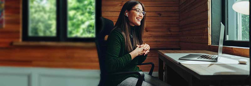 Smiling woman with glasses on a video call at a home office desk