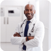 African American male doctor smiling with arms crossed in a hospital hallway.