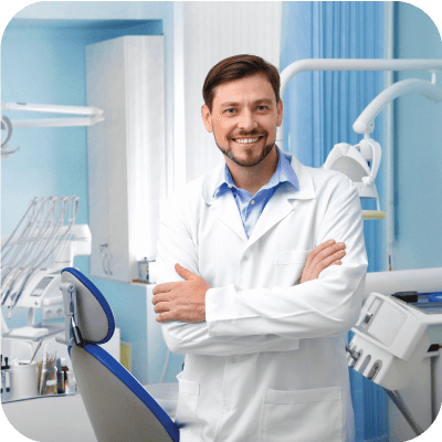 Male dentist smiling with arms crossed in a dentist office.