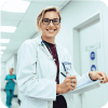 Female physician in hospital corridor writing on a clipboard.